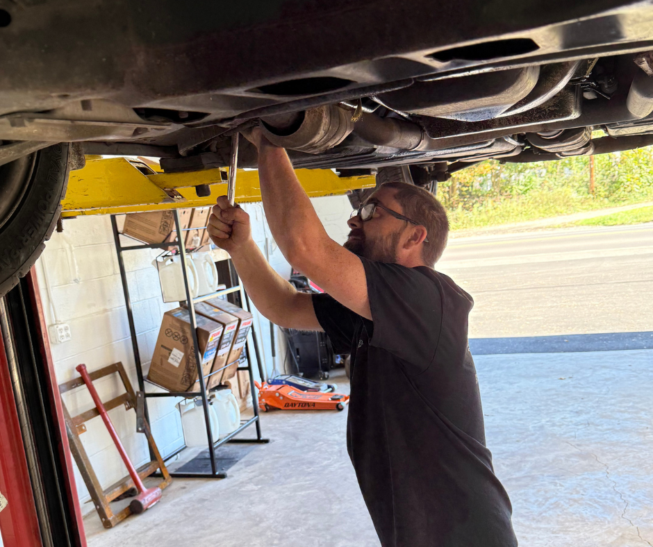 Auto technician repairing a vehicle wheel on a lift inside a repair shop