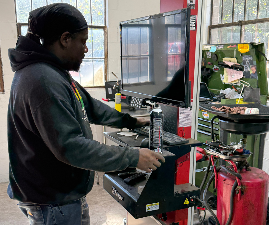 Auto technician operating vehicle diagnostic computer inside a repair shop